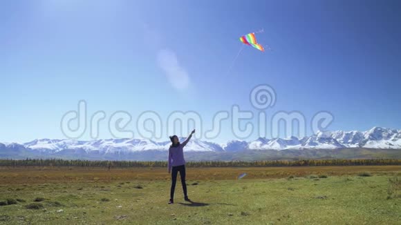 一位年轻女子在高山和冰川的田野里放风筝视频的预览图