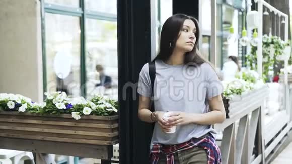 美丽的年轻女子一边喝咖啡一边等待视频的预览图
