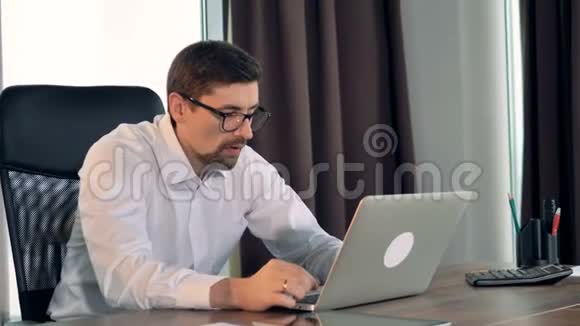 一个商人在笔记本电脑上打字并叹息视频的预览图