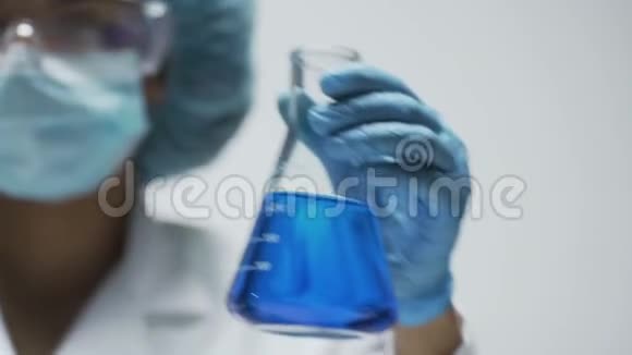 研究人员在锥形瓶中搅拌明亮的蓝色液体观察反应视频的预览图