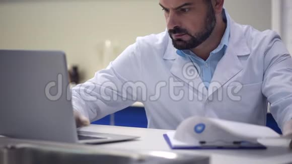 在笔记本电脑上工作时输入数据的严重男性研究员视频的预览图