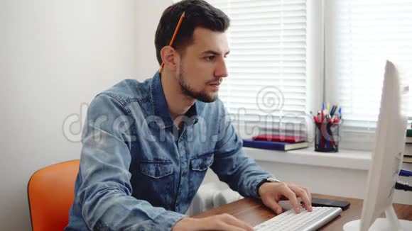 年轻的商人在时尚的现代办公室工作电脑用铅笔和笔记本做笔记计算机视频的预览图
