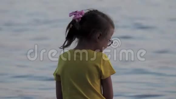 一个戴着眼镜和黄色T恤的小女孩在木墩上玩得很开心那个女孩在水中尿着脚跑着视频的预览图