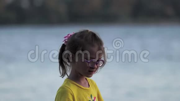一个戴着眼镜和黄色T恤的小女孩在木墩上玩得很开心那个女孩在水中尿着脚跑着视频的预览图
