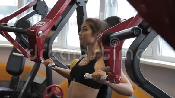 健身妇女在室内健身房的机器上做胸部提升视频的预览图