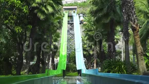 人们在暑假在水上乐园玩水上滑梯室外水上公园带管和滑梯绿色视频的预览图