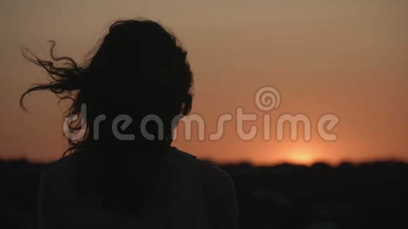 女人看日落日出的黑暗轮廓头发随风飘扬神秘之谜视频的预览图