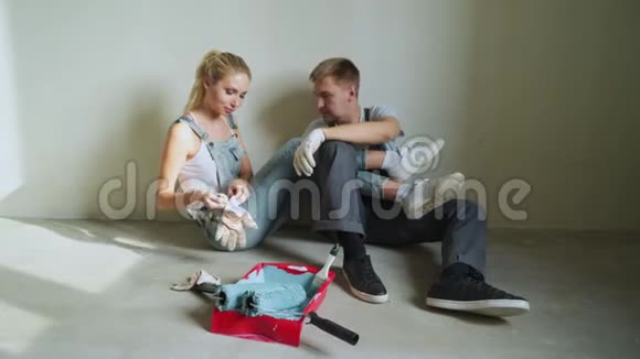 年轻的家庭夫妇用滚筒粉刷公寓或房子里的墙壁视频的预览图