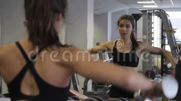 年轻女子运动员在室内健身房做横向举手动作加载三角肌视频的预览图