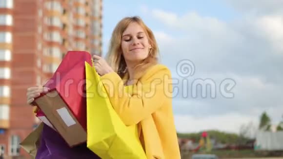 带包的年轻女人购物后很高兴商店附近有五颜六色的袋子的女人在商店里销售金发客户视频的预览图
