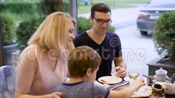 快乐的父母和他们的孩子在餐馆里一起享受披萨嘲笑父亲故事视频的预览图