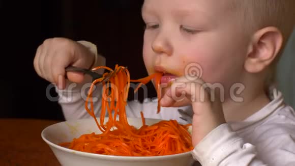 有趣的金发男孩正在他弟弟旁边的厨房里吃韩国胡萝卜沙拉孩子们在一起很快乐视频的预览图