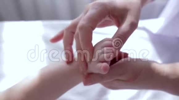 按摩足部治疗师用手缓慢地揉搓婴儿特写的小腿视频的预览图
