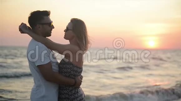 在靠近海洋的日落时有魅力的情侣拥抱蜜月度假概念视频的预览图