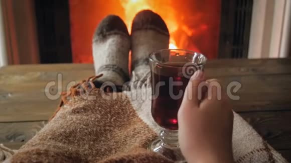 妇女躺在壁炉格子布下喝热茶的慢动作视频视频的预览图