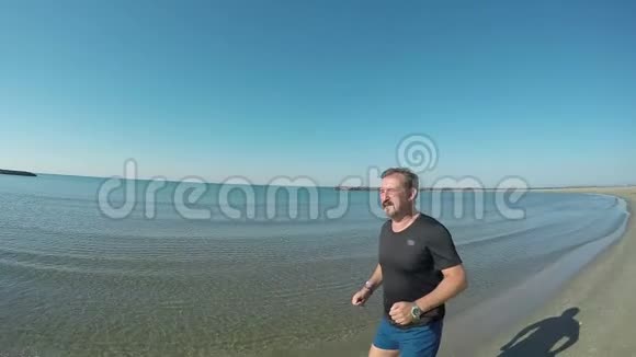 穿着黑色T恤的人沿着海岸奔跑视频的预览图