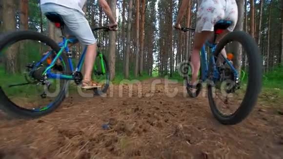 年轻夫妇骑自行车穿过夏季森林的后景视频的预览图