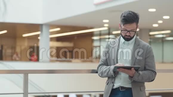 一个留着胡子的人站在商务中心的走廊里还有一张标签视频的预览图