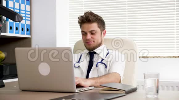 年轻的医生在办公室里用笔记本电脑打字视频的预览图