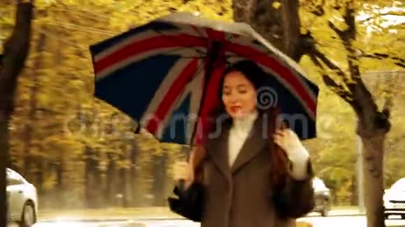 雨天美丽的年轻女子带着雨伞沿着秋巷散步视频的预览图