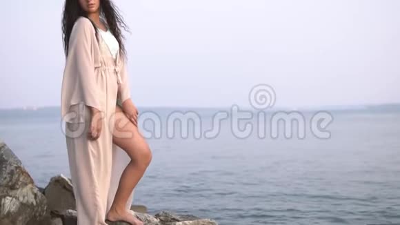 女孩模特站在大海背景下的石头上慢动作视频的预览图