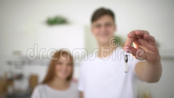 年轻夫妇拿着新房子钥匙近距离拍摄年轻夫妇手拿钥匙从他们的新时尚家在他们的新家视频的预览图