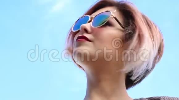 太阳眼镜的年轻时尚女士在蓝天上享受夏日的阳光视频的预览图