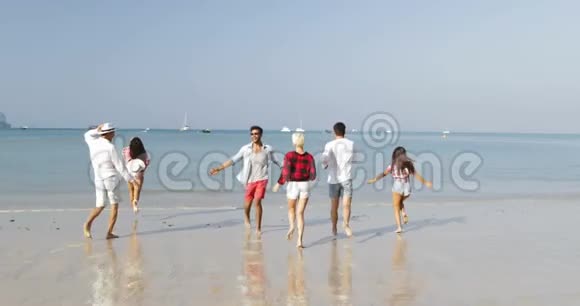 人们成群结队地在海滩上奔跑快乐的男人和女人在度假时举起手来吸引游客视频的预览图