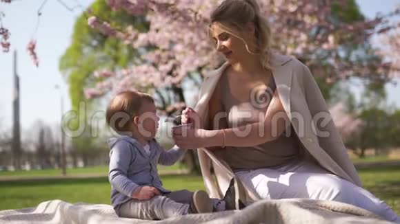 樱花樱花年轻的妈妈和她的小儿子坐在公园里加在拉脱维亚欧洲视频的预览图
