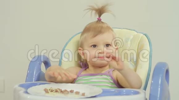 可爱的小女孩吃意大利面用手从盘子里拉食物视频的预览图
