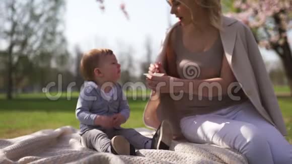 樱花樱花年轻的妈妈和她的小儿子坐在公园里加在拉脱维亚欧洲视频的预览图