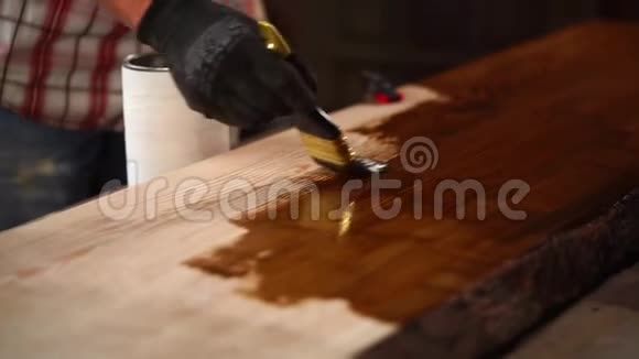 人正在油漆车间的木板表面涂上棕色漆视频的预览图