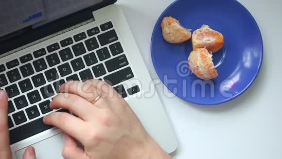一个男人正在用笔记本电脑工作在键盘上键入文本不时地吃着一只躺在碟子上的普通话上面有刺视频的预览图