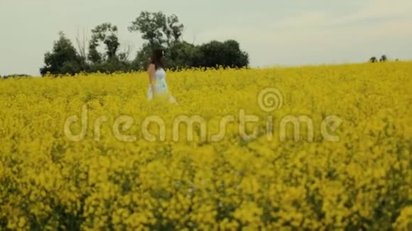 美丽的女孩走在黄花的田野里微笑和欢笑视频的预览图