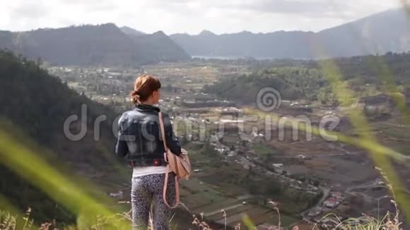 年轻的女人带着智能手机和背包在美丽的山背景上巴图火山巴厘岛视频的预览图