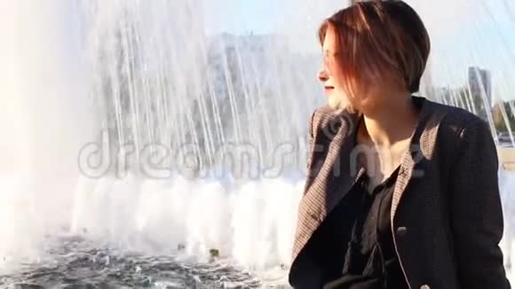 日落时分年轻时尚的女人坐在喷泉上视频的预览图