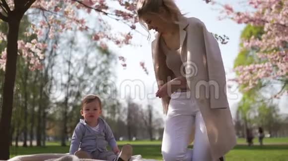 樱花樱花年轻的妈妈和她的小儿子坐在公园里加在拉脱维亚欧洲视频的预览图
