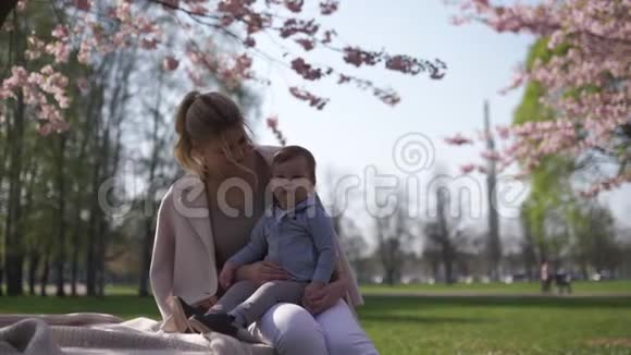 樱花樱花年轻的妈妈和她的小儿子坐在公园里加在拉脱维亚欧洲视频的预览图