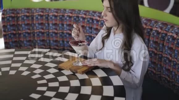 快乐的女孩在咖啡馆的桌子上吃美味的果冻4K视频的预览图