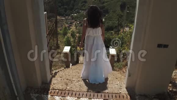 年轻女子穿着白色连衣裙站在山上别墅的楼梯上背景是城市视频的预览图