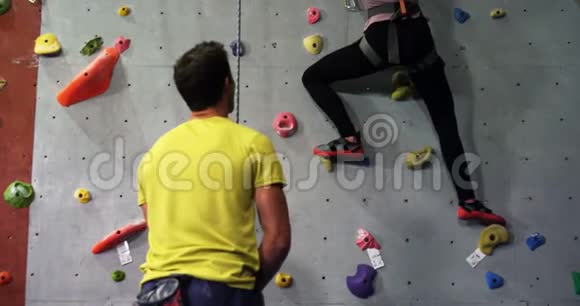 教练协助一名女子攀登人造墙视频的预览图