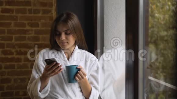 有电话的女人从窗户往外看视频的预览图