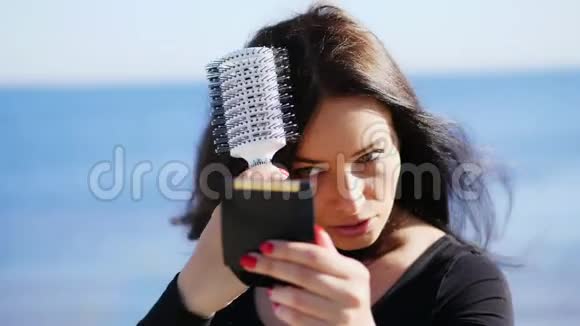 一位40岁的美丽女子的肖像深褐色的眼睛是绿色的她在粉盒里照着小镜子视频的预览图