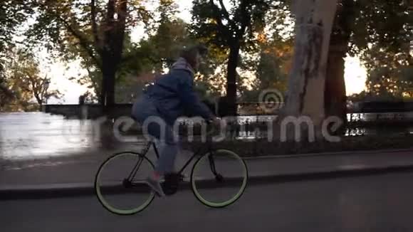 迷人的女性骑自行车在早晨公园或林荫大道一位骑着徒步自行车的年轻女子的侧景视频的预览图