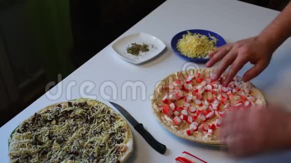 准备披萨一个男人把蟹棒切成披萨桌子旁边是一个比萨饼准备做饭和其他配料视频的预览图