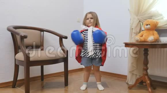 可爱的小女孩戴着拳击手套穿着红色斗篷展示了她作为超级英雄的力量视频的预览图