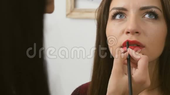 美容师用红色唇膏染红女人的嘴唇视频的预览图