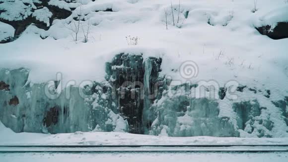 年轻人走在铁路小径上沿着覆盖着冰的山崖视频的预览图