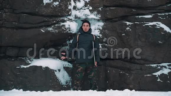 年轻人在白雪覆盖的岩壁前谈话视频的预览图