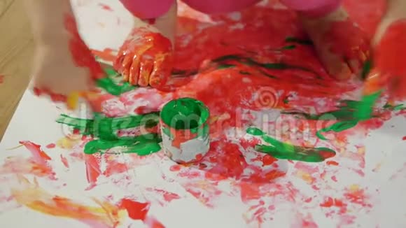 特写小女孩用脏兮兮的颜料手指在地上画着一张大白纸视频的预览图